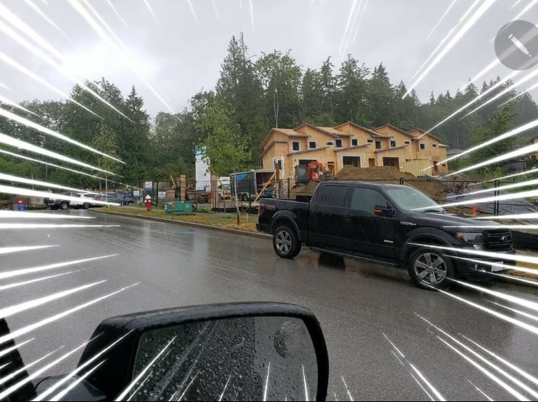 A Black Color Car Moving in Front of a House